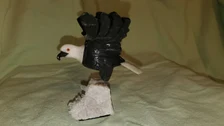 Hand-carved stone eagle with white head and dark body, perched on a natural stone base